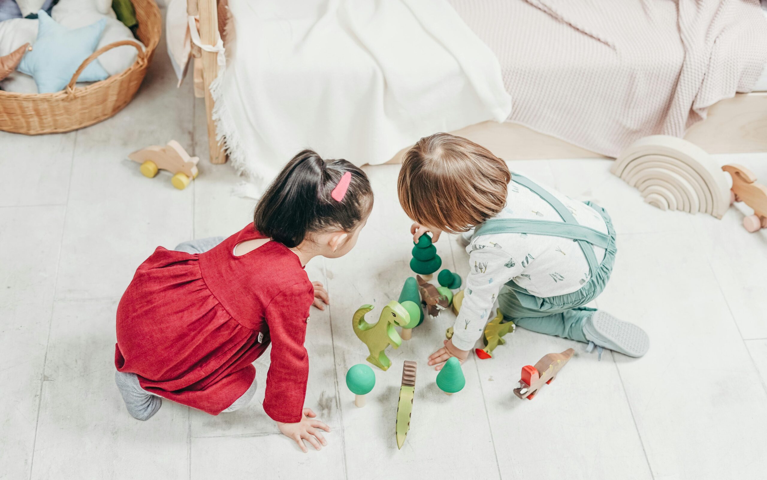 Two children happily playing with wooden toys in a cozy playroom.